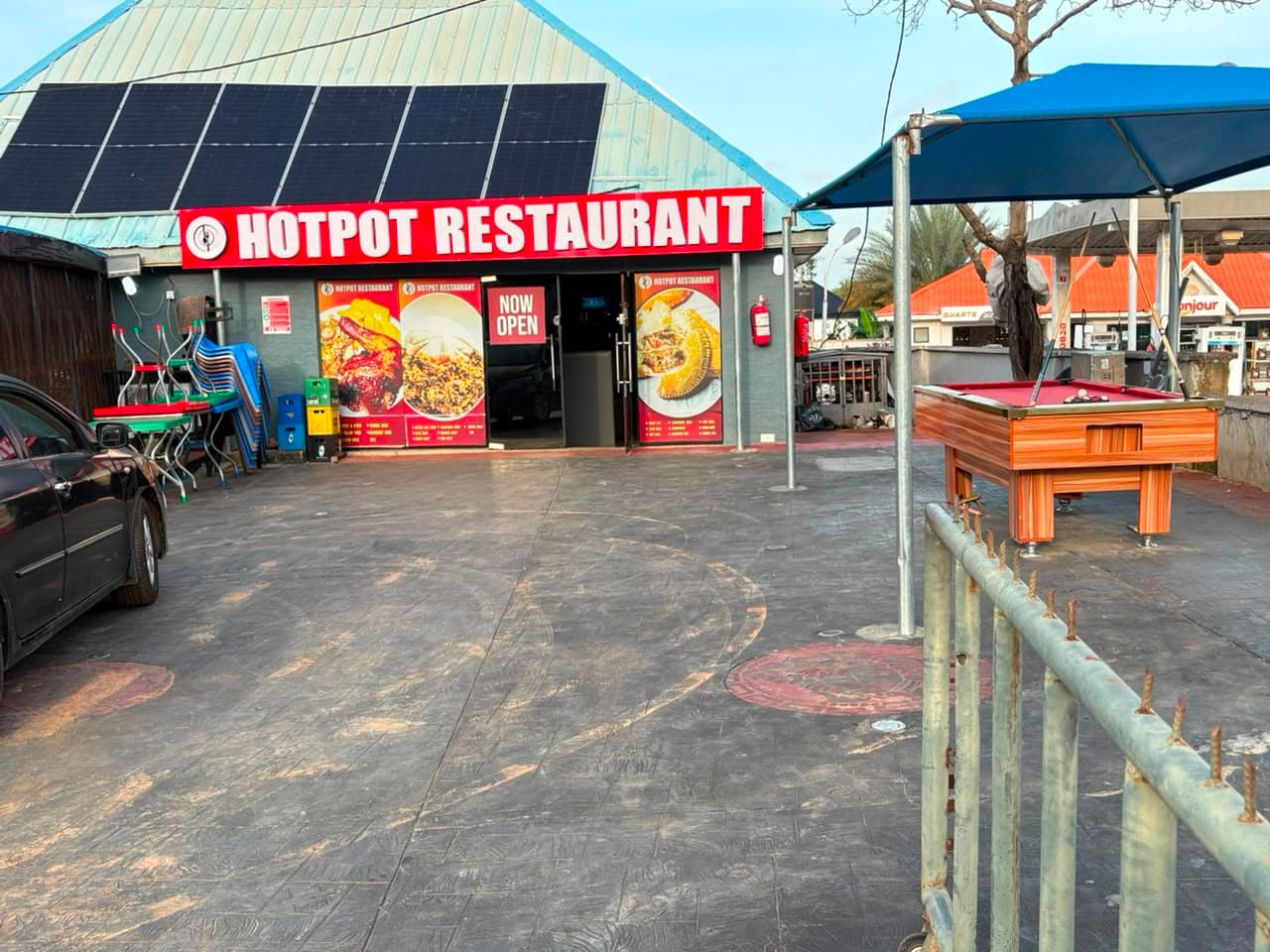 The Hotpot Restaurant storefront by day with the red sign board, forecourt and outdoor pool table